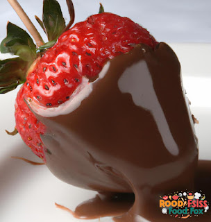 Image of a chocolate covered strawberry being drizzled with melted milk chocolate.