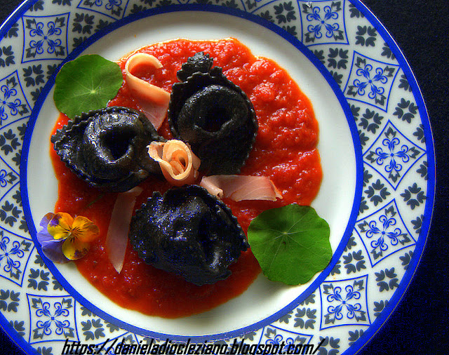 Ravioli al nero di seppia farciti con pesce spada su crema di pomodoro