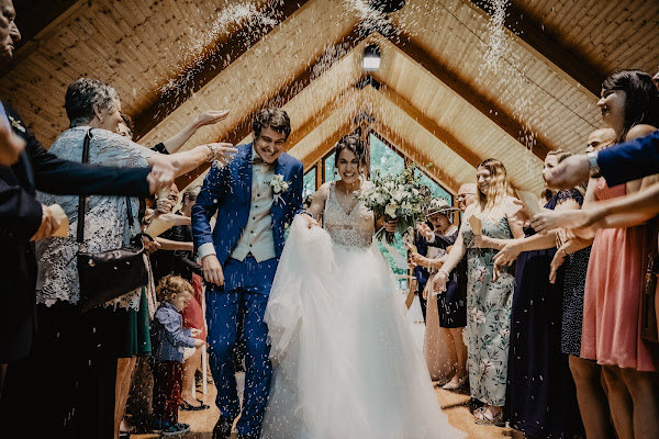 groom and bride running down aisle through guests after getting married