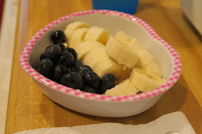 Blueberries and a banana, sliced, in a bowl. 