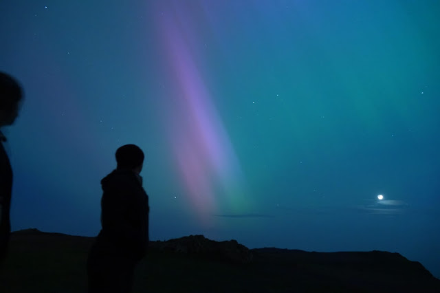 Two figures silhouetted against the northern lights
