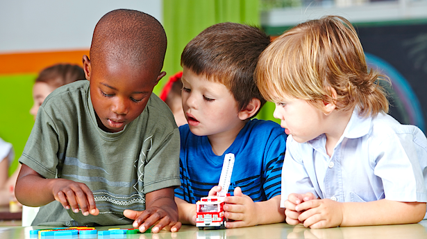 Three-children-in-kindergarten-playing-with-building-blocks-and-cars