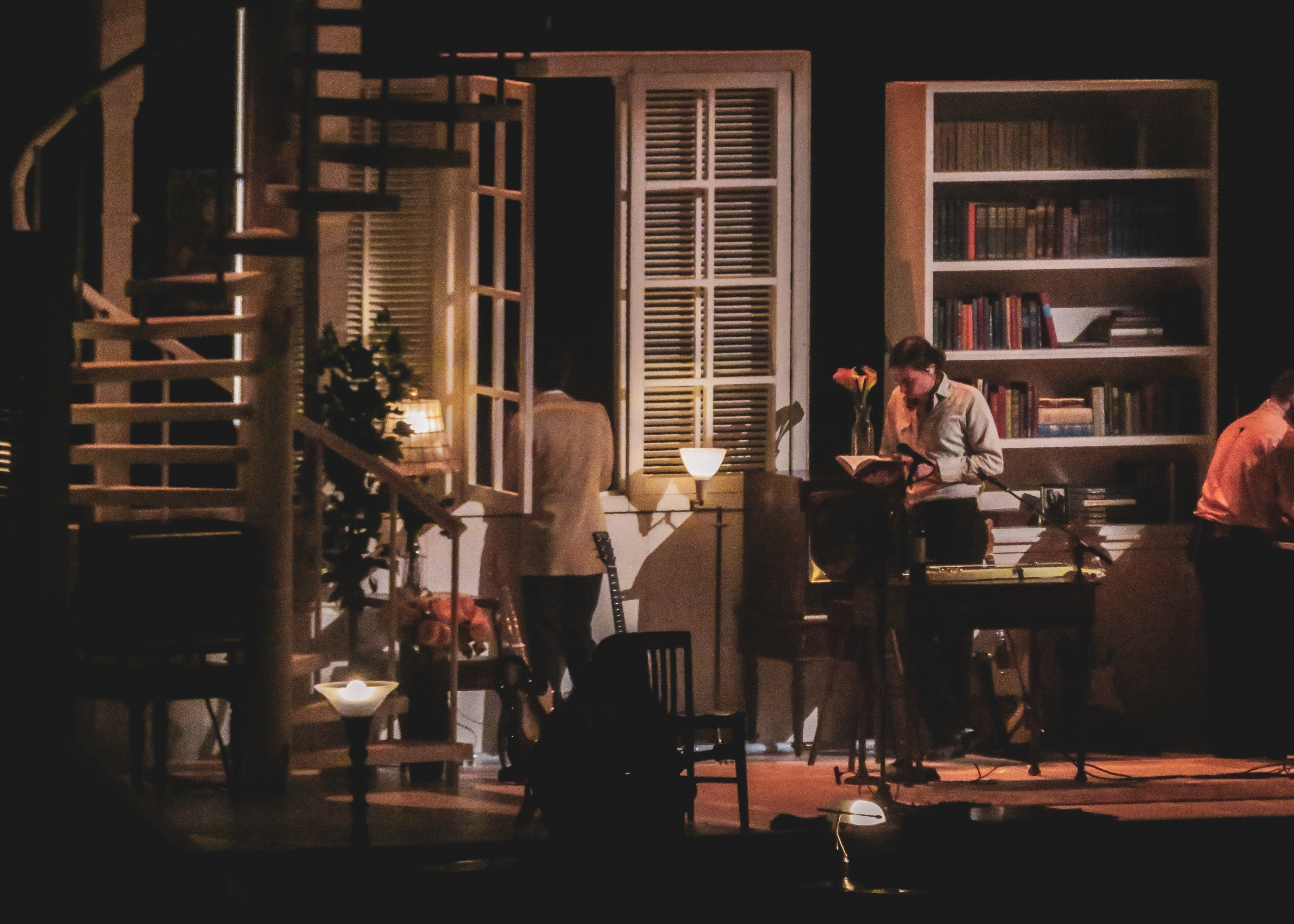 Matt Healy with his back facing the camera looking out of a window on stage at The 1975 'At their very best' tour