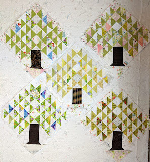 Fine pine tree quilt blocks sewn. Leaves represented by light green triangles with a few other colors like blue, pink, and darker green for depth. for depth