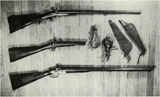 Regiments went into battle armed with shotguns. Ranged beside two shot pouches and two typical sporting powder flasks are Lefaucheux double pinfire gun such as achieved limited sale pre-War through New York agents Hartley, Schuyler and Graham, and was esteemed by French-ancestry Southrons resident in Louisiana. Middle is true “sawed off shotgun” by Ezekiel Baker, having heavy 10 barrels bored for shot or ball. Piece has single non-selective trigger, made in 1850! Bottom is Greener 10 bore waterfowler popular along eastern shore and Mississippi flyway. Cut to 20 and occasionally fitted with bayonet, such first quality sporting arms made Southern cavalryman formidable fighter.