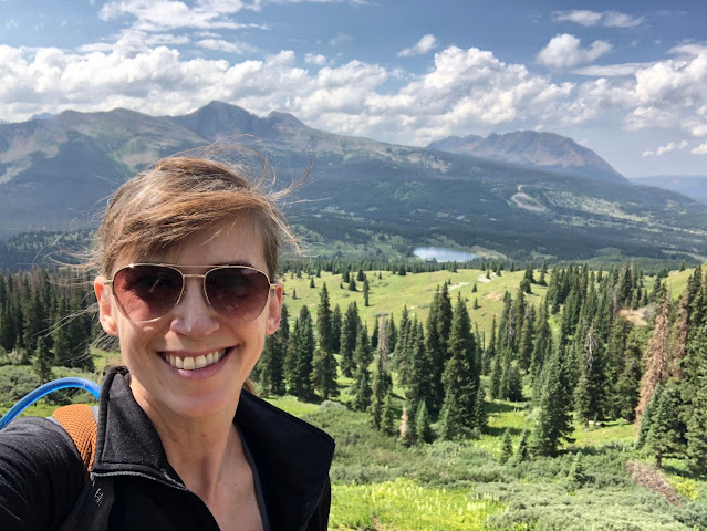 woman in the mountains in summer with forest behind her