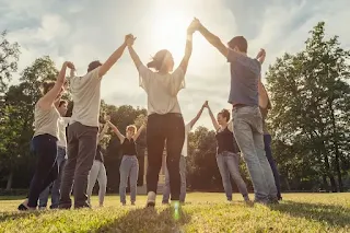 people holding hands raised high and forming a big circle