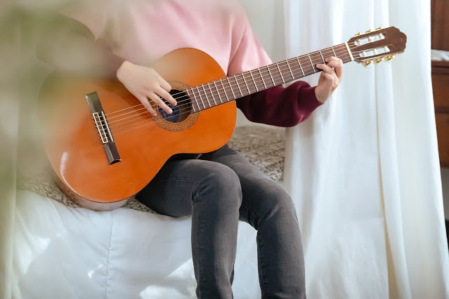 A picture of a woman playing the D chord on guitar