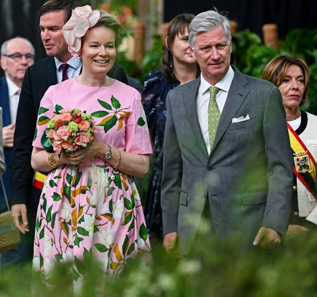 Queen Mathilde wore a degrade magnolia flower print belted poplin dress from Oscar de la Renta. Gold earrings and green pumps by Natan