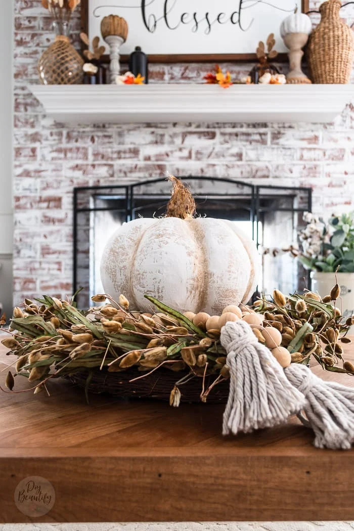 pumpkin layered on pussy willow wreath wrapped with a wood bead garland