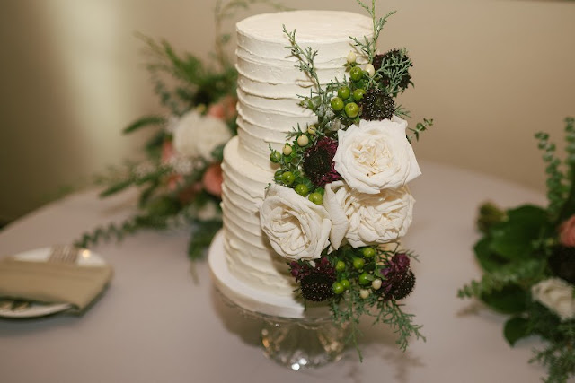 two tier white cake with berries and flowers