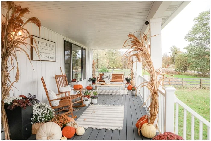 fall porch with mums, pumpkins and cornstalks