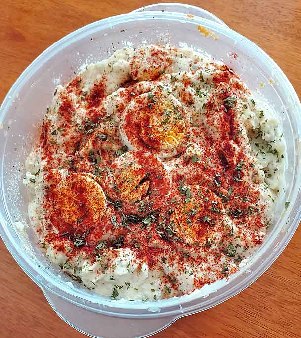 this is a bowl of classic potato salad with hard boiled eggs on top garnished with paprika