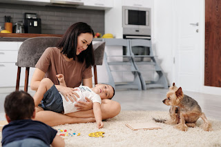 A mother playing with her two sons and a dog on the floor