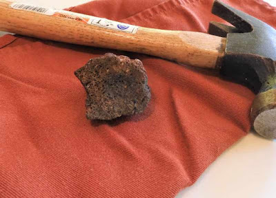 A picture of a rock and a hammer on a cloth napkin.