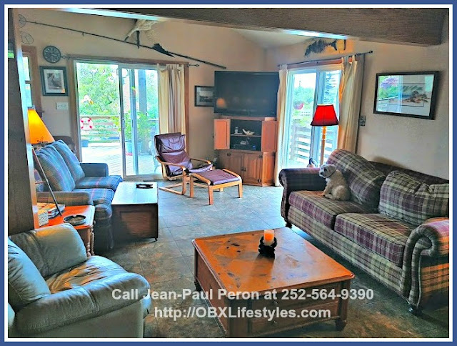 The living room of this stunning canal front home for sale in Corolla NC is connected to the large deck through sliding glass doors. 