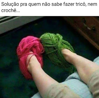 Post. No topo lê-se: Solução pra quem não sabe fazer tricô, nem crochê... Abaixo, a foto das pernas do joelho para baixo, e em cada pé, um novelo de lã usado como pantufa . No esquerdo, um vermelho e no outro, verde.