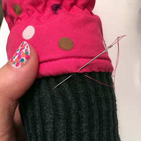 Needle sewing a pink polka dot snow mitten glove held by cute multi colored polka dot nail art 