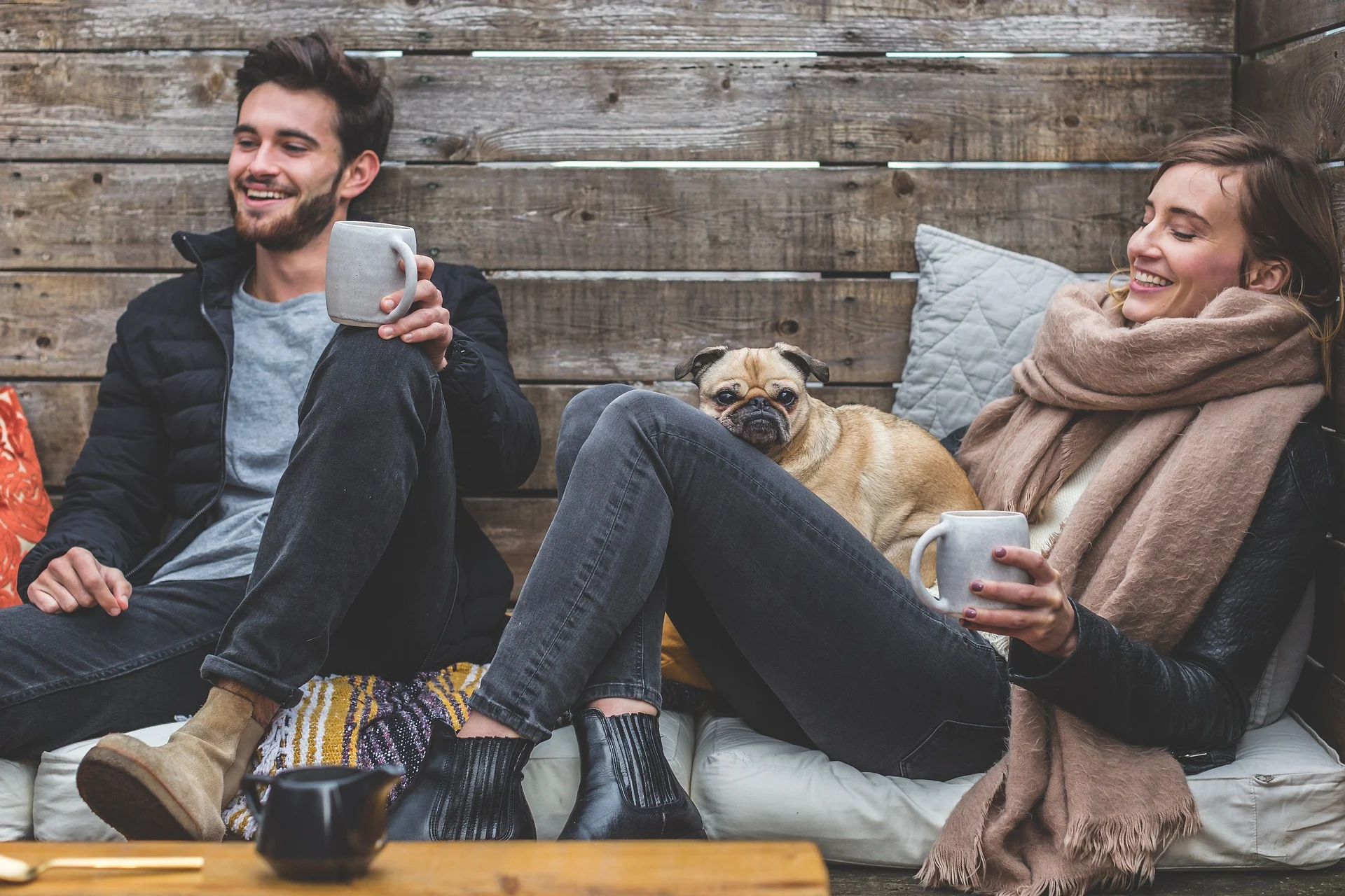 Two friends on a cozy sofa, sipping coffee, and sharing laughter with their faithful dog, portraying the warmth of social connections.