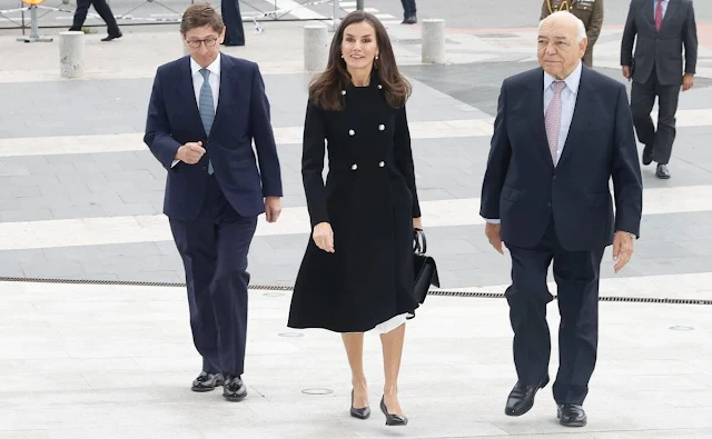 Queen Letizia wore a black v-neck silk shirt by Sandro. Carolina Herrera double-breasted wool coat. Adolfo Dominguez skirt