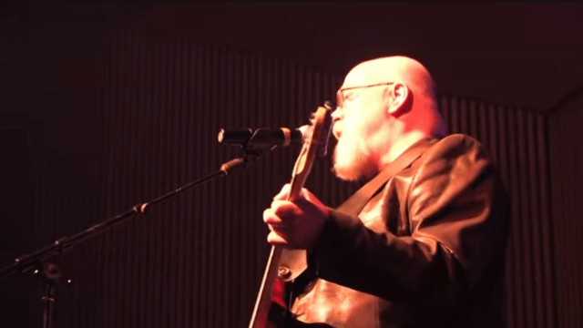 2/3 Bald Bearded Old Daddy Wearing A Gorgeous Leather Blazer Playing Guitar And Singing