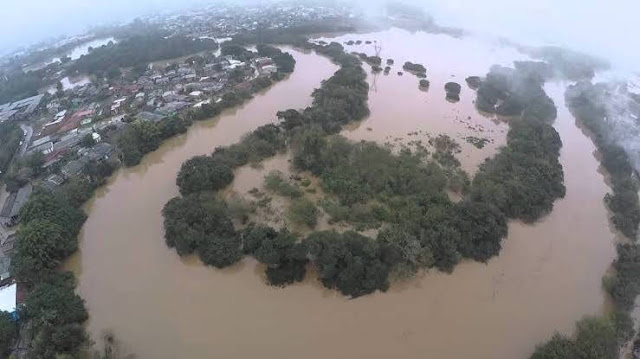 A foto mostra as curvas do Rio dos Sinos transbordando é enchente perigosa.