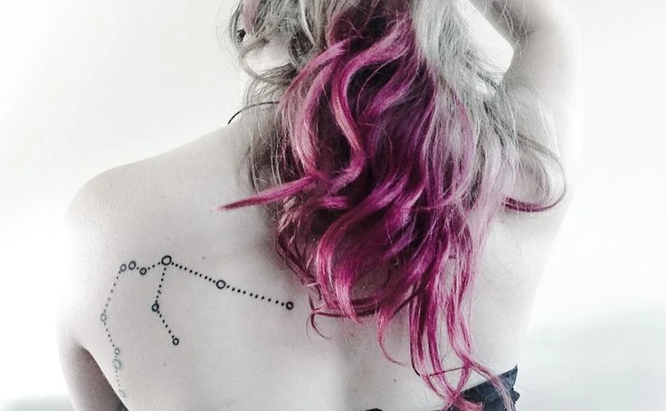 chica que lleva el pelo de colores y que tiene un tatuaje de la constelación de acuario en la espalda