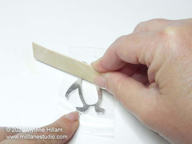 Burnishing the tape on the back of the keychain with a wooden stick