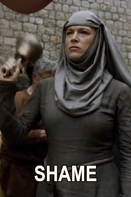 Image from season 5 of Game of Thrones. A woman in plain robes and a head dress is walking through a crowded medieval-style fantasy city street. She has a serious and stern look on her face, and she is ringing a hand bell. The caption "Shame" is written across the bottom of the image.