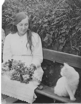 Seated girl with flowers and white cat