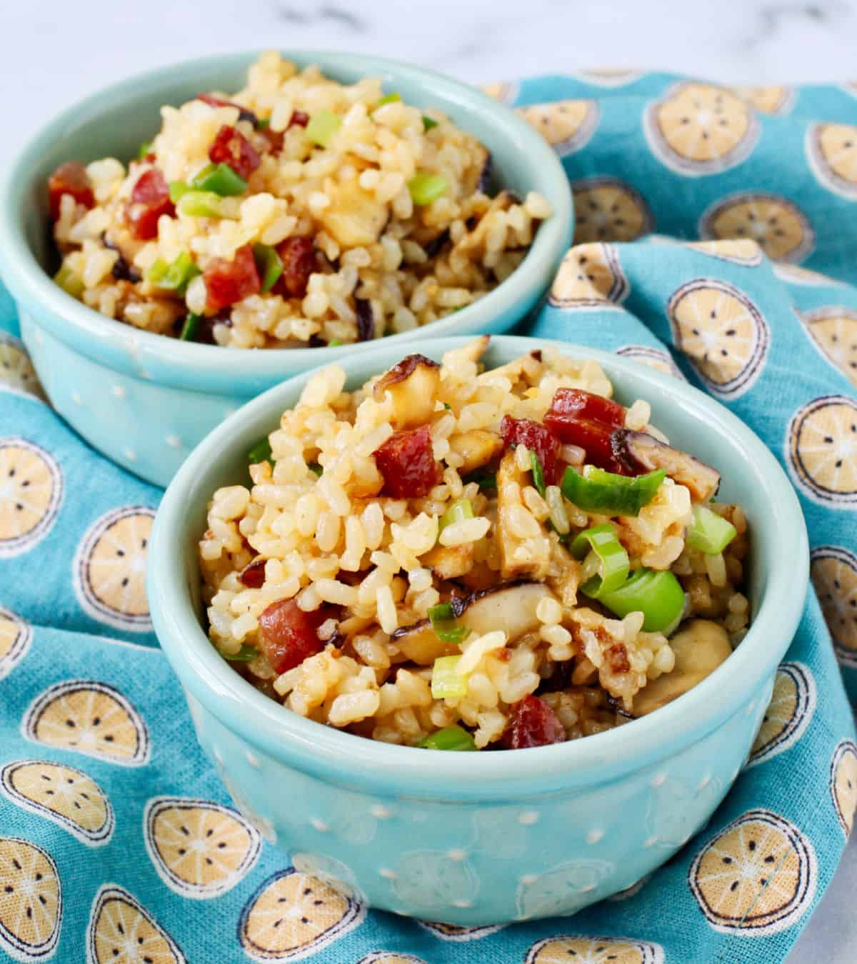 Two small blue bowls of Fried Sweet Rice with Chinese Sausage.