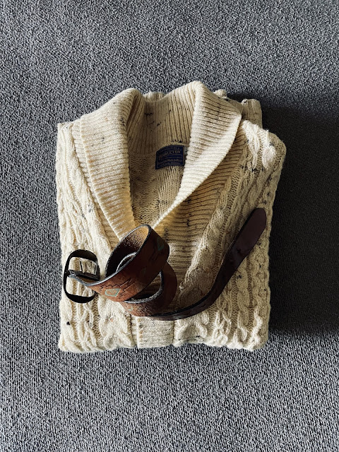 A flat lay of a vintage sweater and belt