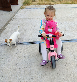 Cycling her trike with her giant care bear (and Thelma)