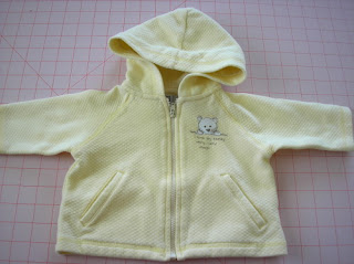 An infant jacket with welt pockets, screen printing, and decorative stitching