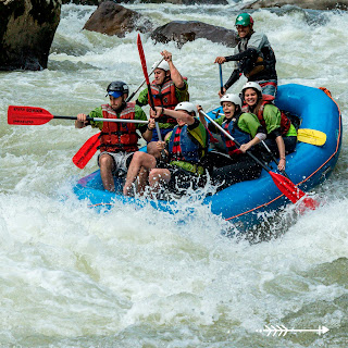 Grupo de aventureros llenos de emoción mientras hacen rafting y atraviesan rápidos desafiantes en el río.