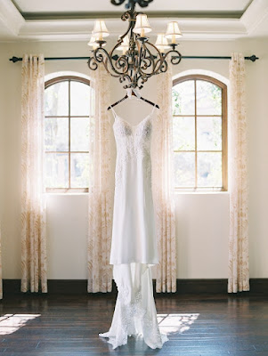 wedding dress on hanger placed on black chandelier