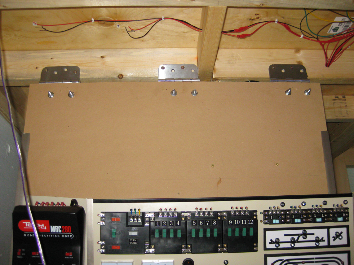 Model railroad control panel installed to the underside of wood benchwork with 3 steel hinges