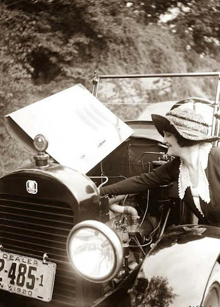 Woman checking auto engine. 1920