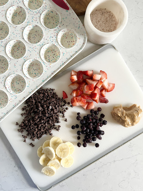 Mini muffin silicone pan next to a cutting board tray of fresh fruit.