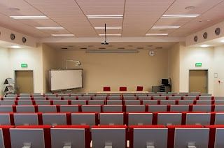 Empty lecture room, with a flipboard and rows of seats
