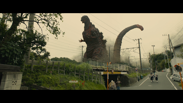 Godzilla towering over people and a bridge