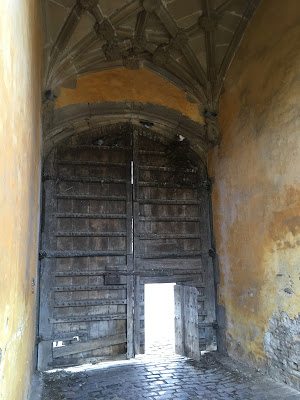 LArge, closed wooden gates with a smaller open postern gate