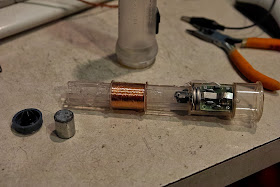 The insides of a "shake" flashlight, showing the magnet, coil, circuit board and the two non-rechargeable CR3032 lithium coin cells.