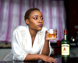 Black woman drinking Jamesons whiskey.