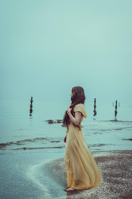 Mujer con vestido de novia teñido en amarillo en la orilla del mar