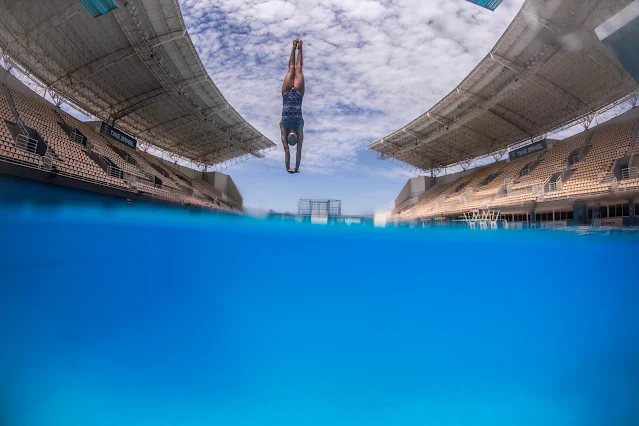 Atleta mergulhando na piscina já na parte final do salto