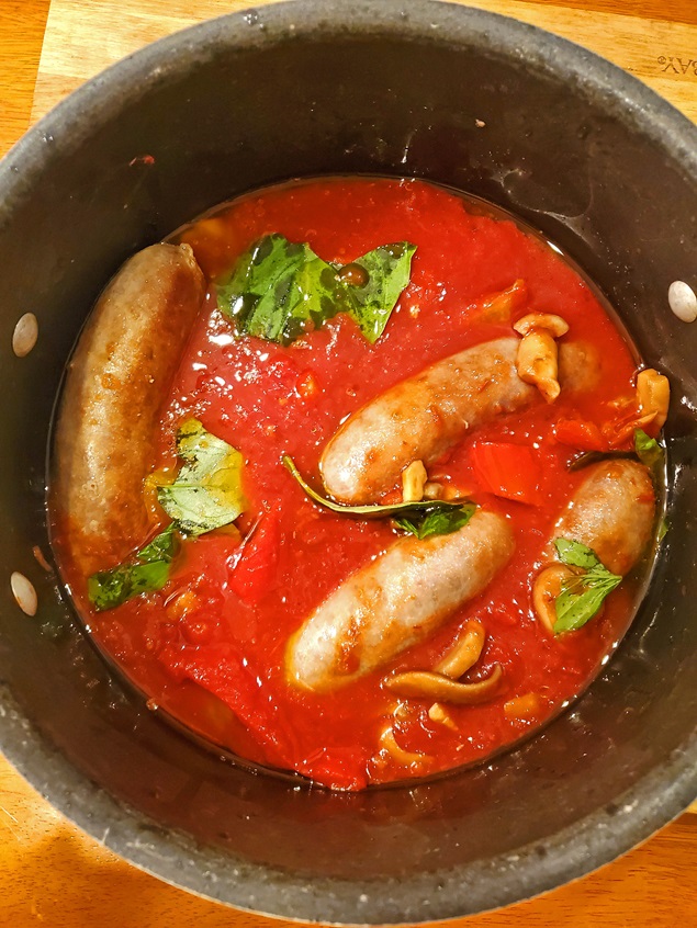 sausage in wine sauce for sandwiches in a big pot simmering with basil
