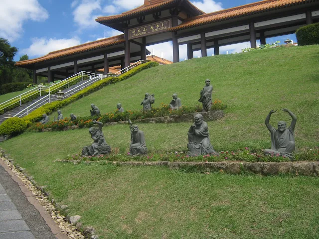 Estátuas de vários budas no caminho que leva para a entrada do pátio central