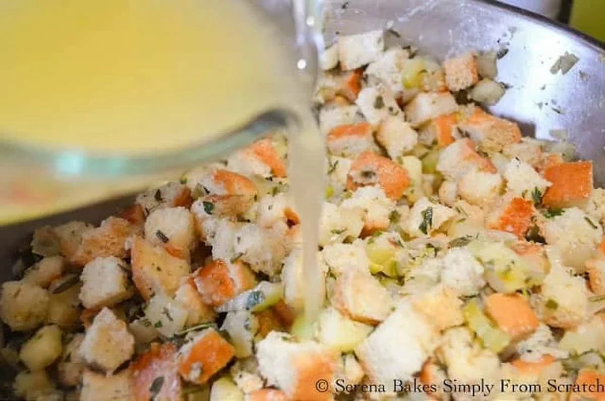 Sautéed Vegetables added to Bread Cubes with Chicken Stock being poured over the top in a crock pot.