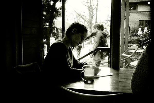 Una chica escribe en la mesa de una cafetería.